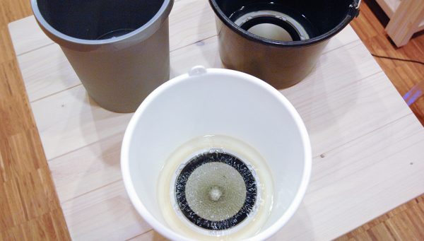 Gisela Motta - Chora Chuva - Installatie met 16 emmers gevult met water met 16 speakers op 6 tafels en 2 banken en 8 stereo versterkers (detail)