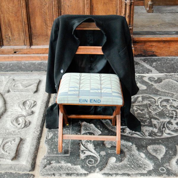 Christian Boltanski - Attente - 15 stoelen met 15 jassen