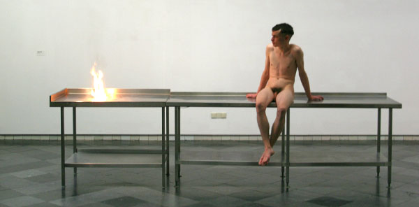 Roger Hiorns - Zonder Titel - RVS keukentafels, vuur en jongeman