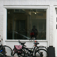 Flinke stukken klei hangen aan vlastouw aan een houten installatie. Iets verder in de galerie liggen vergelijkbare ladingen klei op een tafel. Het is rauw en doet denken aan hompen [&hellip;]